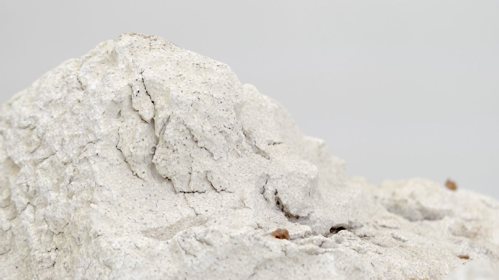 A white styrofoam mass with a mound of fine excavated plastic dust beside it