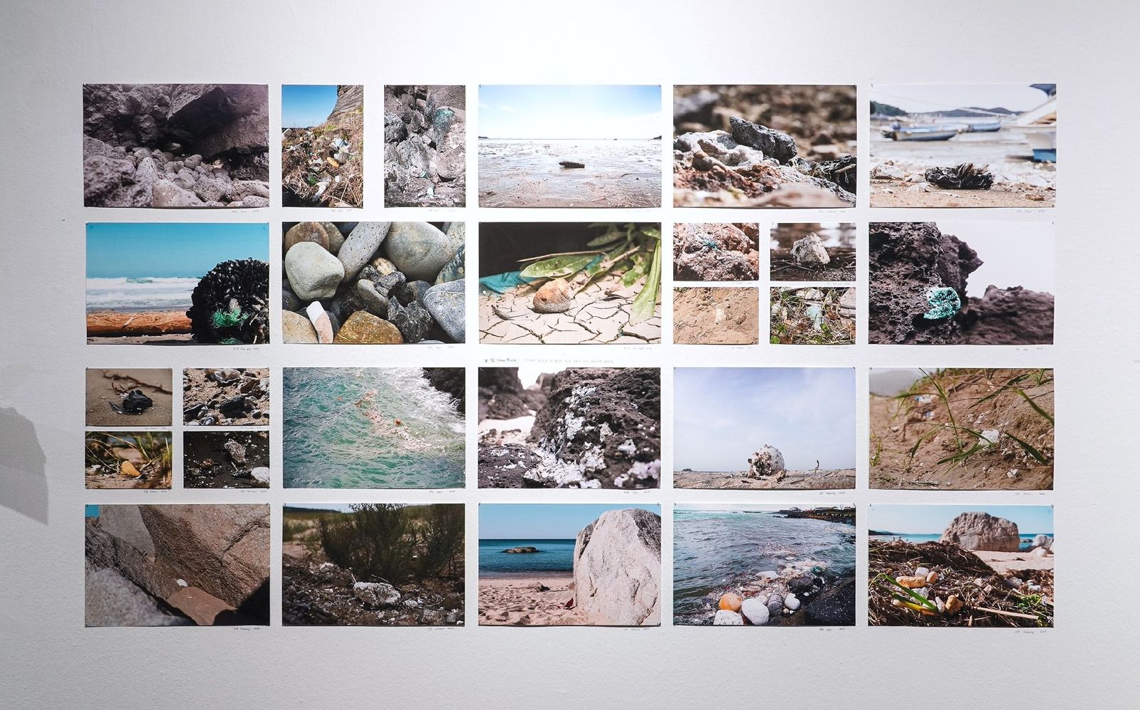 A grid of field photographs of shorelines and New Rock sites installed on a gallery wall