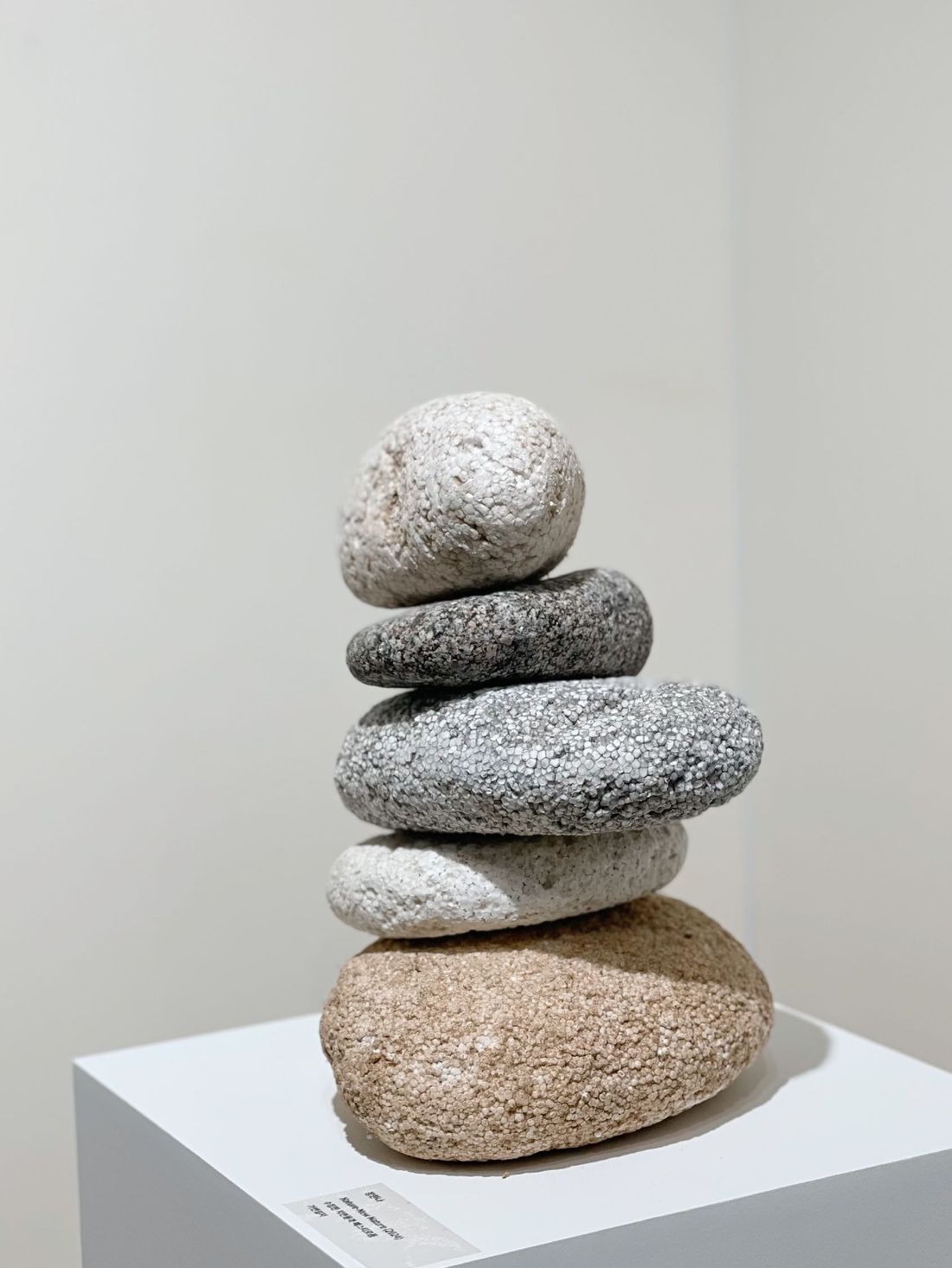 A cairn of rounded stones and New Rocks stacked on a white plinth